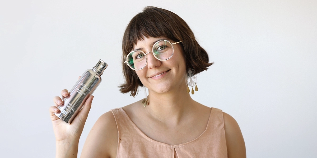 A brunette woman holds up a K-Beauty product.